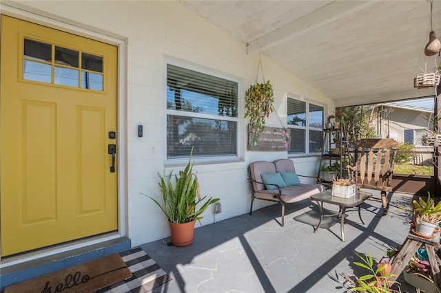 entrance to property featuring concrete block siding and covered porch