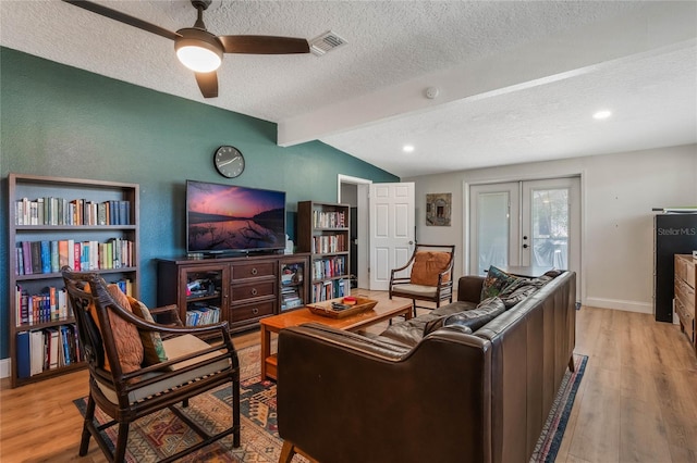 living area with lofted ceiling with beams, french doors, light wood-type flooring, and visible vents