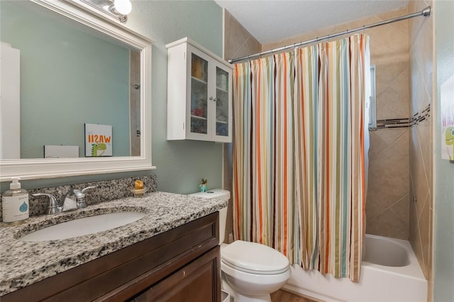 full bath featuring shower / bath combo, a textured wall, vanity, and toilet