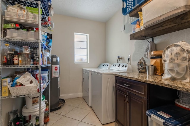 laundry area featuring light tile patterned floors, baseboards, electric water heater, washing machine and clothes dryer, and a textured ceiling