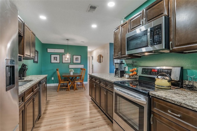 kitchen with stainless steel appliances, dark brown cabinets, hanging light fixtures, and visible vents