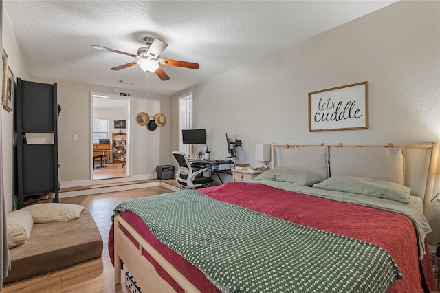 bedroom featuring light wood-type flooring, baseboards, a ceiling fan, and a textured ceiling