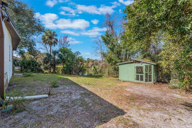 view of yard featuring a fenced backyard, an outdoor structure, and a water view