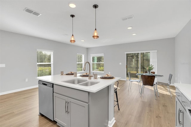 kitchen with sink, gray cabinetry, hanging light fixtures, dishwasher, and an island with sink