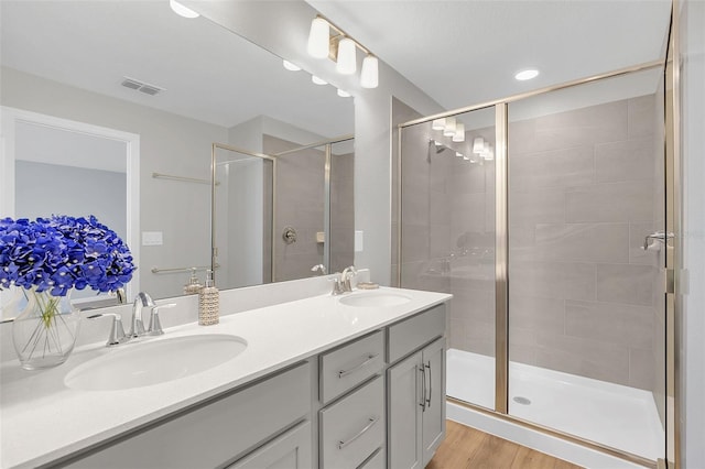 bathroom with wood-type flooring, a shower with shower door, and vanity