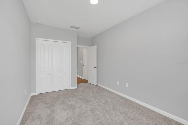 unfurnished bedroom featuring light colored carpet and a closet