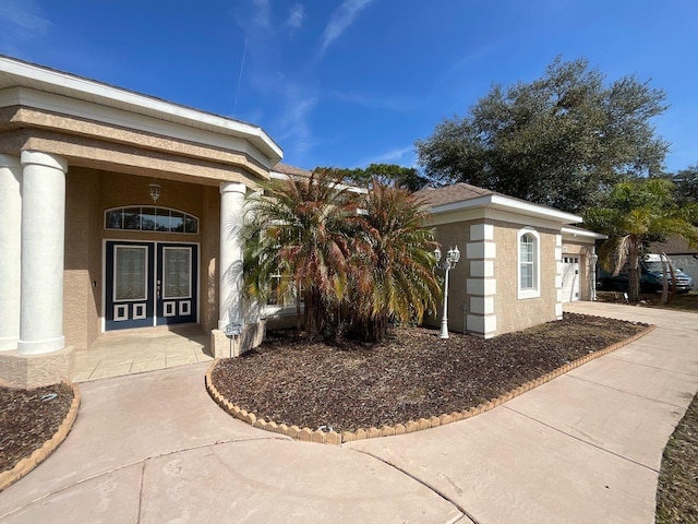 property entrance with concrete driveway, an attached garage, and stucco siding