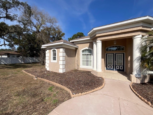 entrance to property featuring a porch, fence, and stucco siding