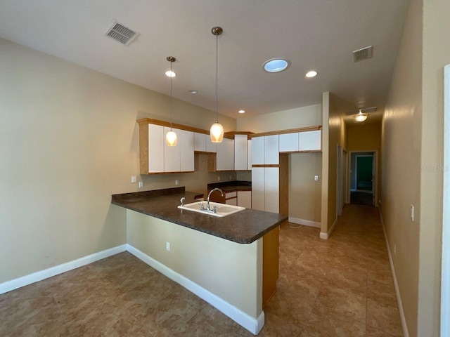 kitchen with kitchen peninsula, sink, hanging light fixtures, and white cabinets