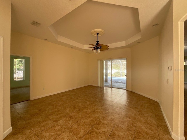 empty room featuring baseboards, visible vents, and a raised ceiling