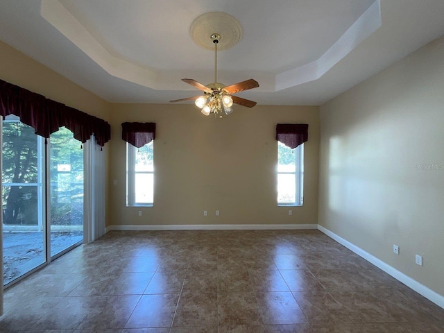 empty room featuring a raised ceiling and ceiling fan