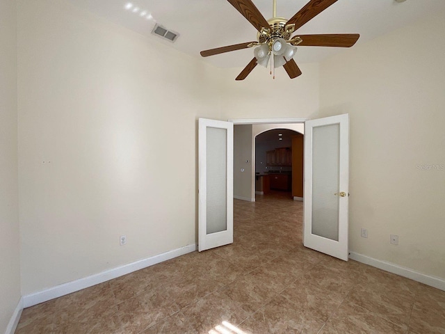 empty room featuring arched walkways, ceiling fan, visible vents, baseboards, and french doors