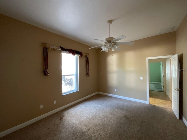 spare room featuring ceiling fan, baseboards, and light colored carpet