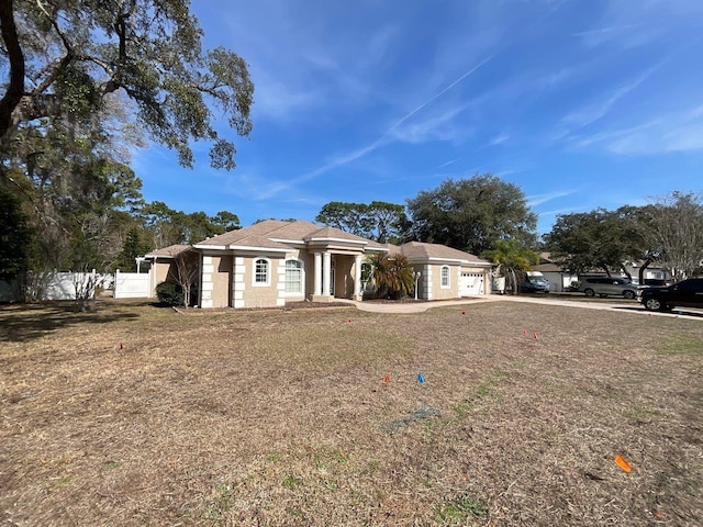 view of front of home with driveway, an attached garage, fence, and a front yard