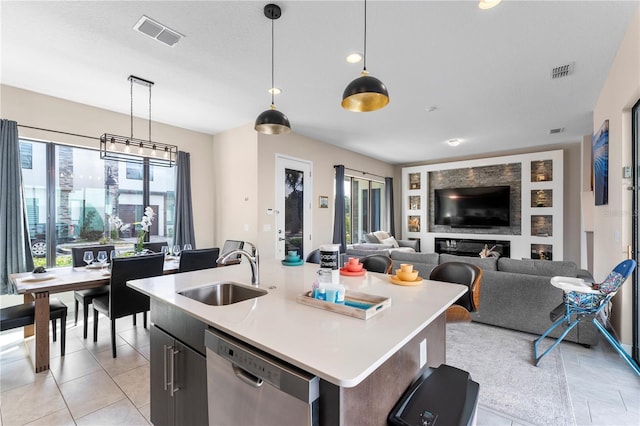 kitchen featuring sink, decorative light fixtures, a center island with sink, light tile patterned floors, and stainless steel dishwasher