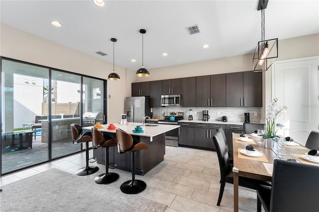 kitchen with pendant lighting, dark brown cabinetry, appliances with stainless steel finishes, and sink