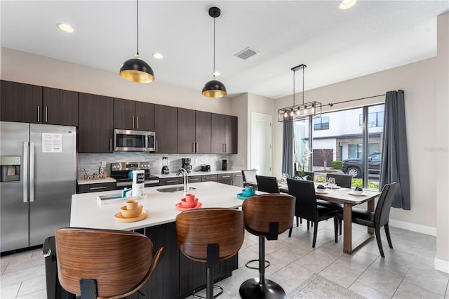 kitchen with dark brown cabinetry, hanging light fixtures, stainless steel appliances, and sink