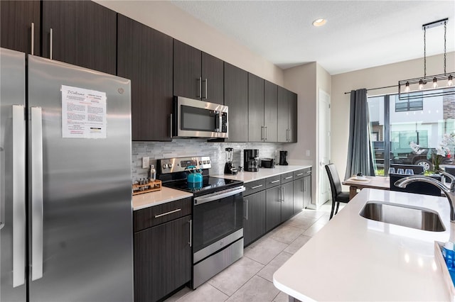 kitchen featuring sink, light tile patterned floors, pendant lighting, stainless steel appliances, and backsplash