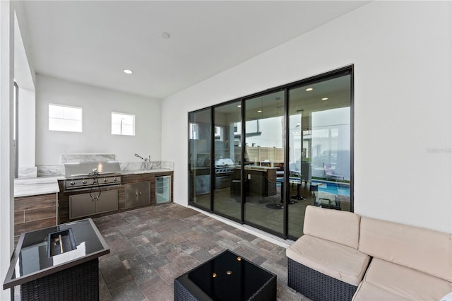 interior space featuring wine cooler, an outdoor kitchen, a grill, and outdoor lounge area