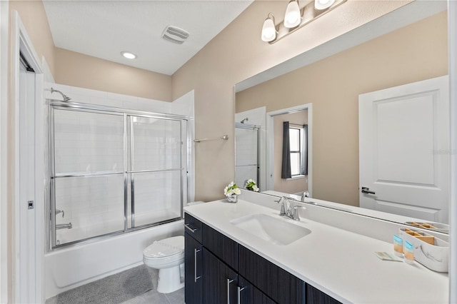 full bathroom featuring vanity, bath / shower combo with glass door, and toilet