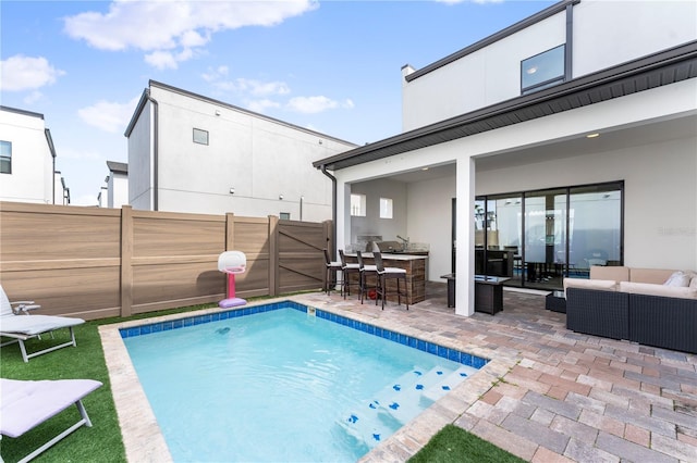 view of swimming pool with a bar, outdoor lounge area, and a patio