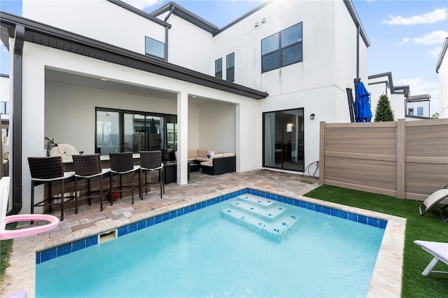 back of property featuring a fenced in pool, an outdoor living space, a patio area, and exterior bar