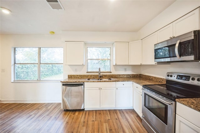 kitchen featuring dark stone countertops, appliances with stainless steel finishes, sink, and white cabinets