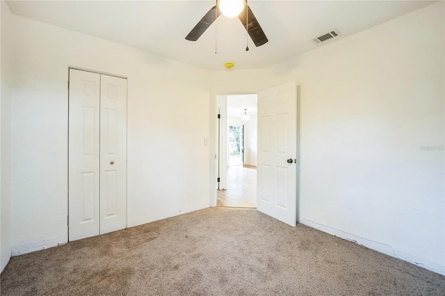 unfurnished bedroom with light colored carpet, a closet, and ceiling fan