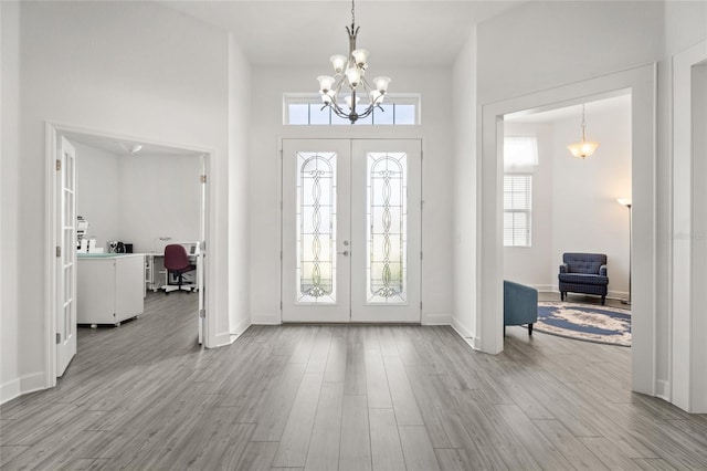 entryway featuring an inviting chandelier, light hardwood / wood-style flooring, french doors, and a healthy amount of sunlight