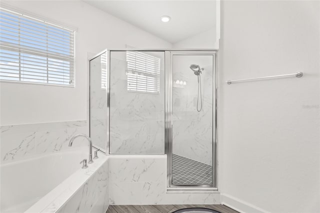 bathroom featuring lofted ceiling, independent shower and bath, and a wealth of natural light