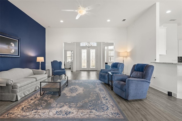 living room with dark wood-type flooring, ceiling fan with notable chandelier, and french doors