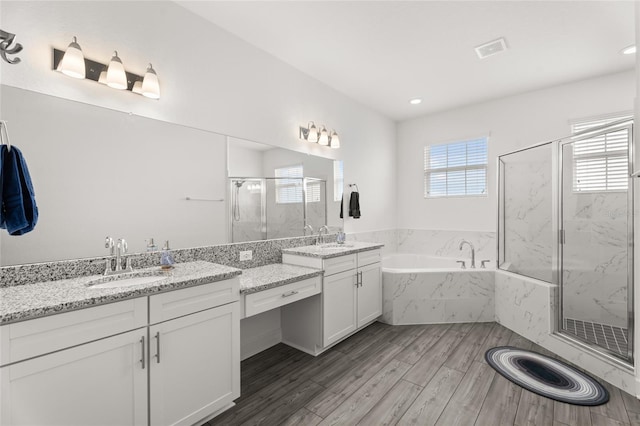 bathroom with a marble finish shower, visible vents, plenty of natural light, and wood finished floors