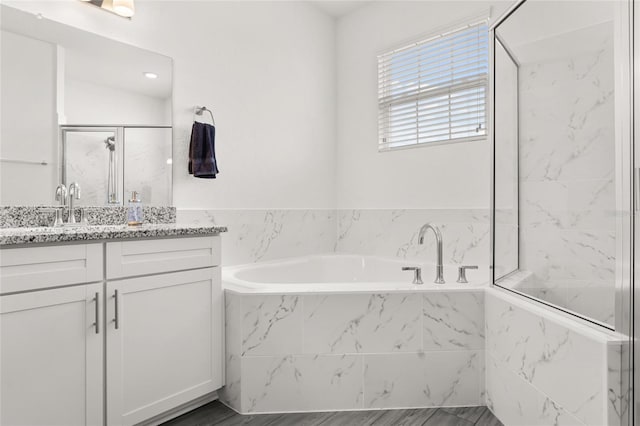 bathroom with a stall shower, vanity, and a garden tub