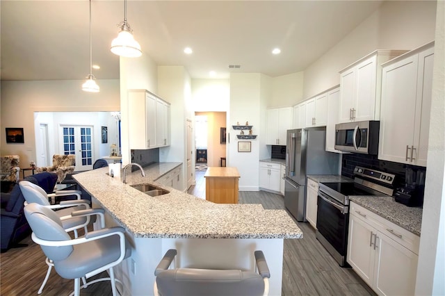 kitchen with a breakfast bar, a sink, a peninsula, appliances with stainless steel finishes, and decorative backsplash