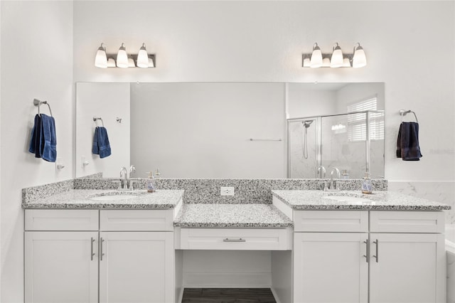 full bath with two vanities, a stall shower, and a sink