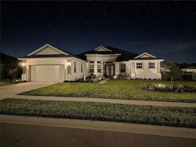 view of front facade featuring a yard, an attached garage, stucco siding, and concrete driveway