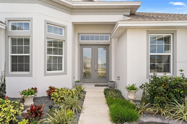 property entrance featuring french doors, roof with shingles, and stucco siding