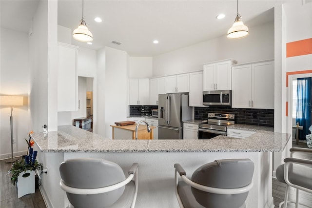 kitchen with a peninsula, visible vents, appliances with stainless steel finishes, a sink, and backsplash