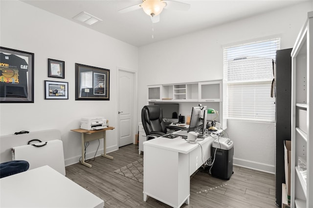 office space featuring light wood-style flooring, baseboards, a ceiling fan, and visible vents