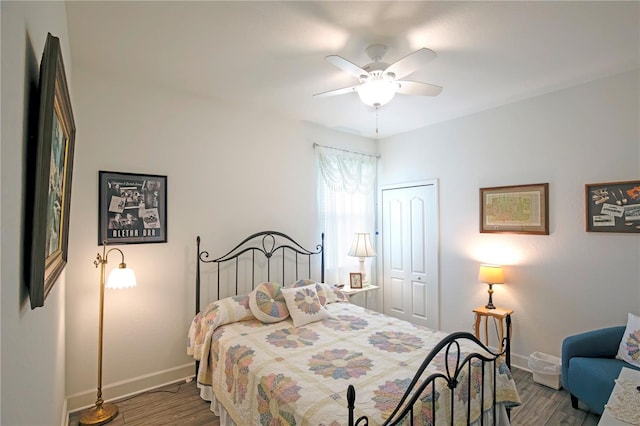 bedroom featuring a ceiling fan, wood finished floors, baseboards, and a closet