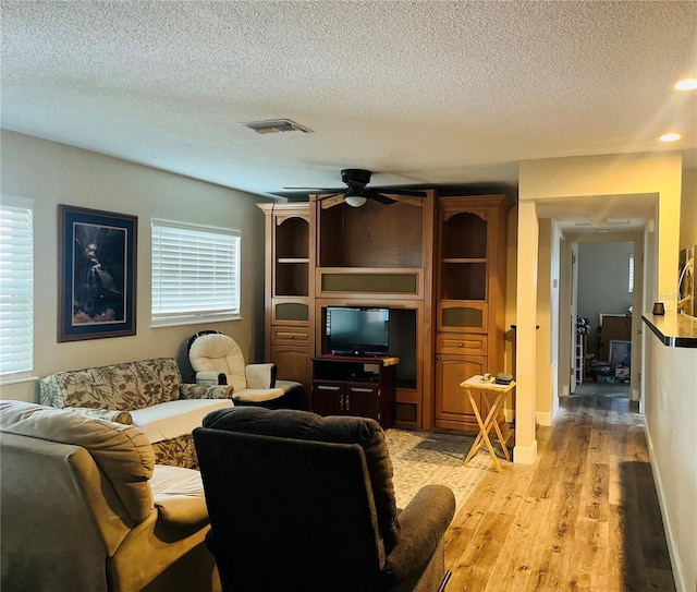 living room with ceiling fan, a healthy amount of sunlight, a textured ceiling, and light hardwood / wood-style floors