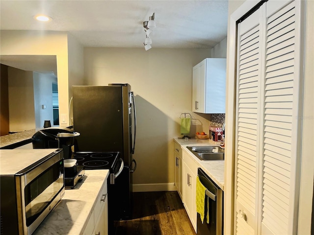 kitchen with dark hardwood / wood-style floors, tasteful backsplash, white cabinetry, sink, and stainless steel appliances