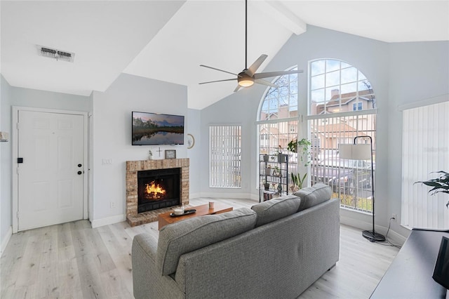 living room featuring high vaulted ceiling, a fireplace, light hardwood / wood-style floors, and beamed ceiling