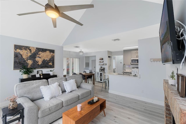 living room featuring high vaulted ceiling, sink, ceiling fan, and light hardwood / wood-style flooring