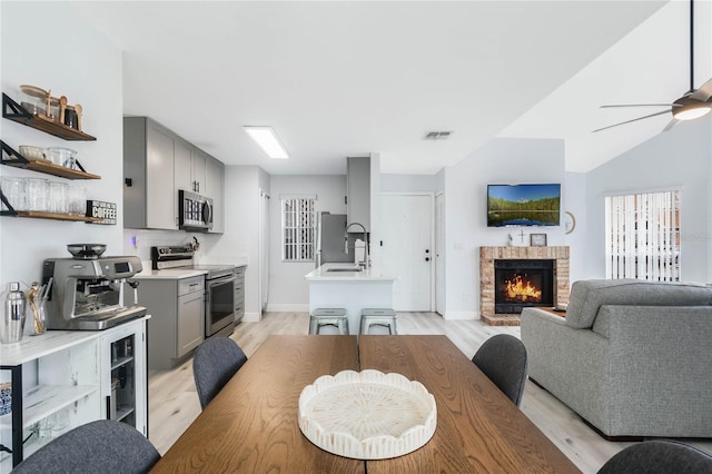 dining space with ceiling fan, a fireplace, and light hardwood / wood-style flooring