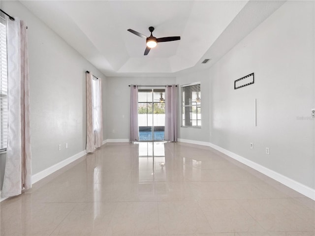 spare room with a raised ceiling and ceiling fan