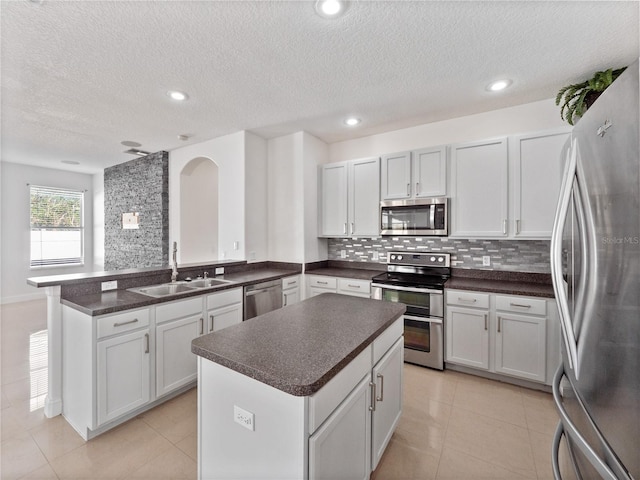 kitchen with a kitchen island, white cabinetry, sink, kitchen peninsula, and stainless steel appliances