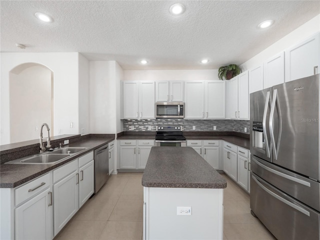 kitchen featuring white cabinetry, sink, light tile patterned floors, kitchen peninsula, and stainless steel appliances