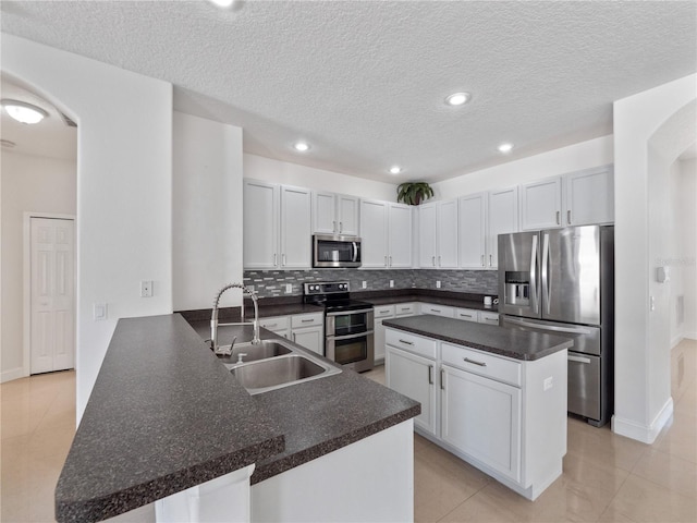 kitchen with stainless steel appliances, sink, white cabinets, and kitchen peninsula