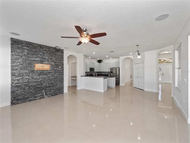 unfurnished living room with ceiling fan, sink, and a textured ceiling